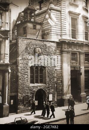 St. Ethelburga's Church, Bishopgate, London, Großbritannien, wie sie in den späten 1940er Jahren vor der Wiederherstellung in ihre heutige Form war. Voll bekannt als St. Ethelburga-die-Jungfrau innerhalb Bishopsgate. Es wurde von der IRA (Irish Republican Army) bombardiert und seitdem restauriert. Es überlebte das große Feuer von London (1666) & ist St. Ethelburga (Adelburga) 7. Jahrhundert Äbtissin der Barking Abbey gewidmet. Es hat eine Reihe von Änderungen einschließlich Wiederaufbau im 15. Jahrhundert und die Zugabe eines kleinen quadratischen Glockenturm im Jahr 1775, Eine Wettervane im Jahr 1671 und eine hölzerne Veranda mit 2 Geschäften (nach unten gezogen 1938). Stockfoto