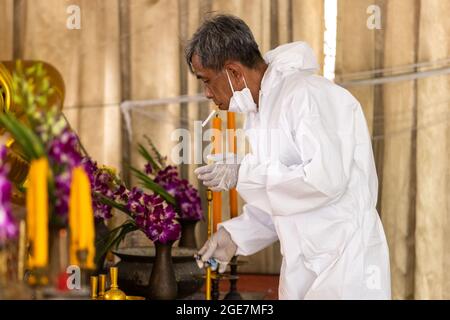 Thonburi, Thailand. August 2021. Ein Bestatter sah, wie er während seiner kurzen Pause im Sutthawat Temple Zigarette rauchte.COVID Delta verbreitete sich in Thailand stark mit 20,000 Infektionen und 200 Todesfällen pro Tag. Nur wenige Tempel akzeptieren COVID-19-Körper, die zu einem Mangel an Krematorien führen, um buddhistische Kremierungsrituale durchzuführen. (Foto: Phobthum Yingpaiboonsuk/SOPA Images/Sipa USA) Quelle: SIPA USA/Alamy Live News Stockfoto