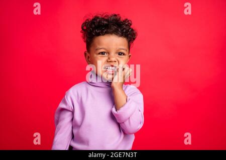 Portrait von attraktiven fröhlich lustigen Jungen beißen Nägel erwartet isoliert über lebendige rote Farbe Hintergrund Stockfoto