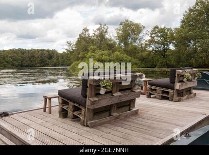 Holzbänke aus alten Paletten mit Blick auf einen Teich Stockfoto