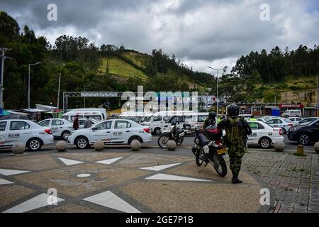 Die Soldaten der kolumbianischen Armee beobachten, wie Fahrer von Fahrzeugen des öffentlichen Dienstes auf der internationalen Brücke Rumitschaca protestieren, die die Länder Kolumbien und Ecuador verbindet und die Öffnung der Grenze fordert, weil die Schließung von COVID-19 die lokale Wirtschaft in Ipiales, Nariño, am 17. August 2021 beeinträchtigt Stockfoto