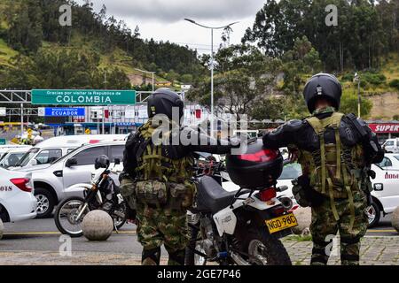 Die Soldaten der kolumbianischen Armee beobachten, wie Fahrer von Fahrzeugen des öffentlichen Dienstes auf der internationalen Brücke Rumitschaca protestieren, die die Länder Kolumbien und Ecuador verbindet und die Öffnung der Grenze fordert, weil die Schließung von COVID-19 die lokale Wirtschaft in Ipiales, Nariño, am 17. August 2021 beeinträchtigt Stockfoto