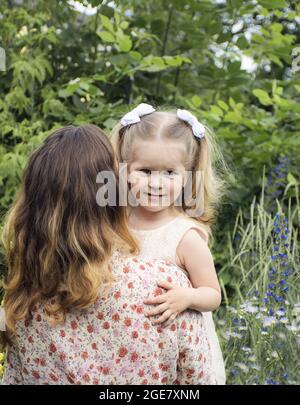 Mutter hält die kleine Tochter in der Natur in den Armen Stockfoto