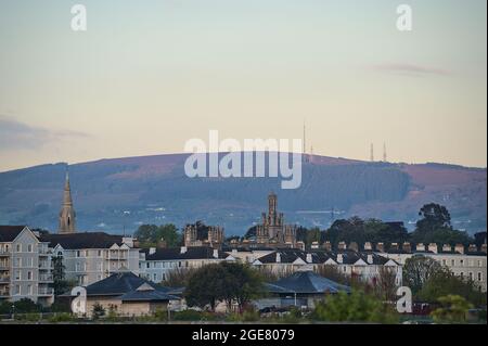 Morgenansicht der Dächer von Häusern, Kirchen und Schlössern und Three Rock Mountain mit Mobilfunkantennen vom Hafen von Dun Laoghaire (West Pier) aus gesehen Stockfoto