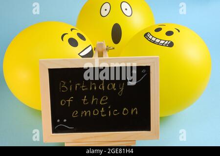 Gelbe Emoji-Ballons und ein Brett mit der Aufschrift Ereignisse auf blauem Hintergrund. Stockfoto
