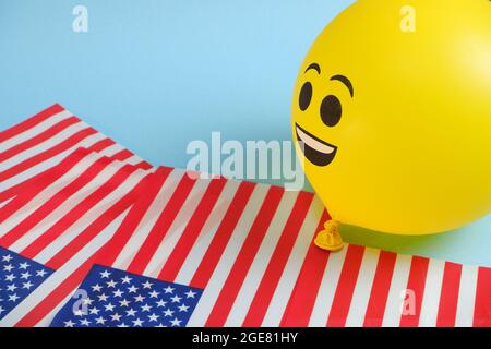 Gelbe Emoji-Ballons mit amerikanischen Flaggen auf blauem Hintergrund. Stockfoto