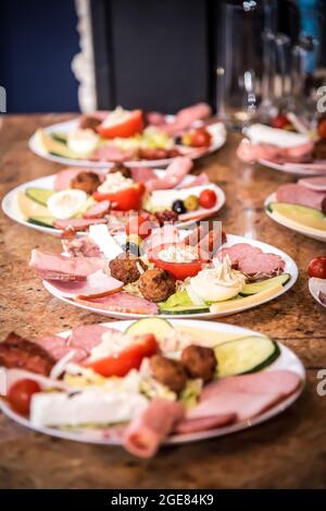 Typische Teller mit rumänischen Vorspeisen auf der Theke, Teller mit gefüllten Tomaten, Gurken, Käse, Hackbraten und viele Arten von Würstchen Stockfoto