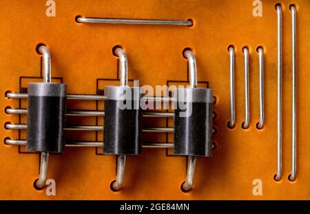 Integrierte Leiterplatte mit gelöteten Widerständen. Elektronische Bauteile, die an der Leiterplatte befestigt sind. Dunkler Hintergrund. Stockfoto