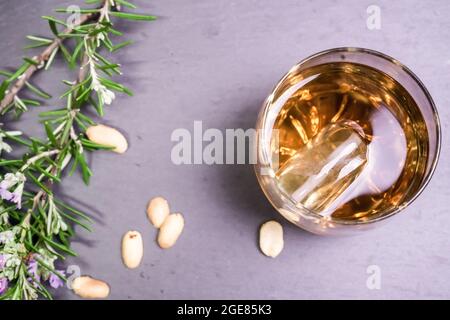 Glas Whiskey mit Walnüssen und einer Rosmarinblume auf einem Steintablett, Draufsicht Stockfoto