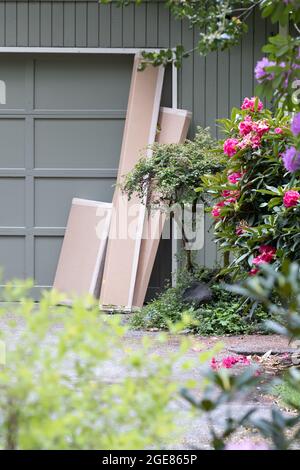 Hauslieferkartons aus Pappe, die vor einer Garage sitzen Stockfoto