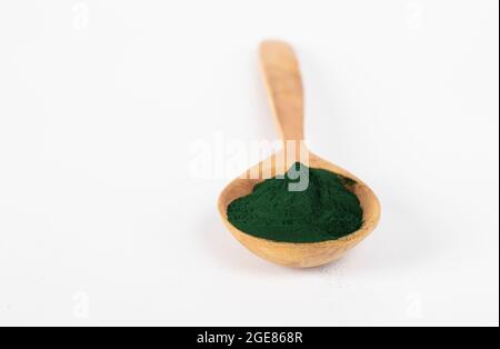 Spirulina-Algenpulver aus kontrolliert biologischem Anbau in Holzlöffel auf weißem Hintergrund. Stockfoto