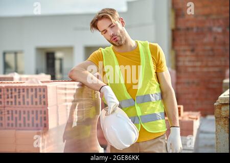 Erschöpfter junger Arbeiter, der eine Pause von der Arbeit einnahm Stockfoto