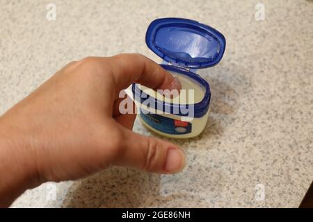 Finger tauchen in eine Vaseline Wanne Stockfoto