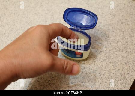 Finger tauchen in eine Vaseline Wanne Stockfoto