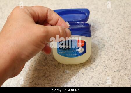 Finger tauchen in eine Vaseline Wanne Stockfoto