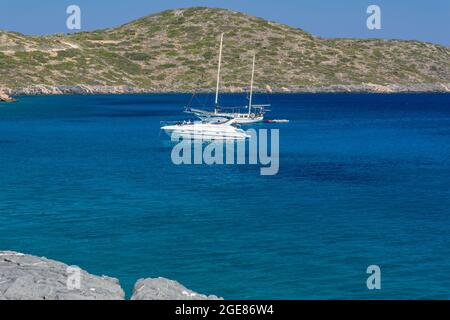 ELOUNDA, KRETA - 11. JULI 2021: Klares Wasser und trockenes Gestrüpp an der Küste in der Nähe der Stadt Elounda, Kreta, Griechenland Stockfoto