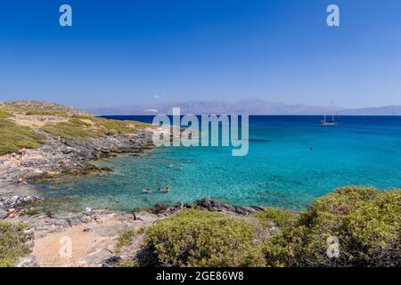 ELOUNDA, KRETA - 11. JULI 2021: Klares Wasser und trockenes Gestrüpp an der Küste in der Nähe der Stadt Elounda, Kreta, Griechenland Stockfoto