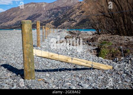 Neuer Pfosten- und Gitterzaun, der die Farmgrenze vom Flussbett im Hochland von Canterbury, Neuseeland, trennt Stockfoto