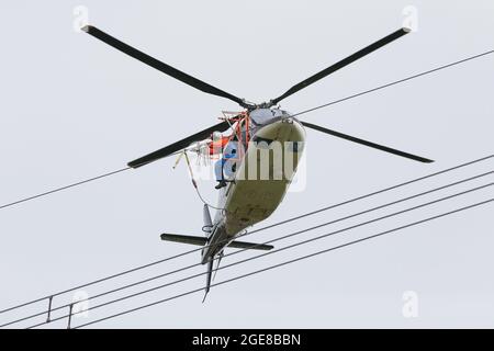 Vogelschutzmarkierungen mit Hilfe eines Hubschraubers und eines außerhalb von Deutschland sitzenden Monteers auf einer Hochspannungsleitung platzieren, Affoldern, 2017-04-10. Stockfoto