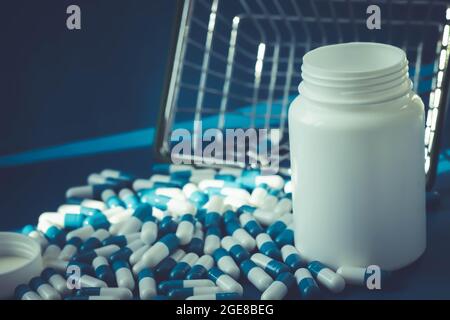 Pillen in einem Lebensmittelkorb. Medikamentenkapseln auf dem Tisch. Käufer in der Apotheke. Medikamente online bestellen. Pillen auf blauem Hintergrund in einer Schachtel. Stockfoto