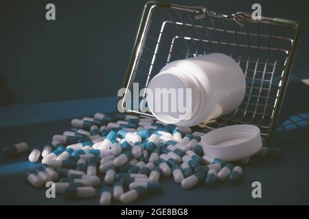 Pillen in einem Lebensmittelkorb. Medikamentenkapseln auf dem Tisch. Käufer in der Apotheke. Medikamente online bestellen. Pillen auf blauem Hintergrund in einer Schachtel. Stockfoto