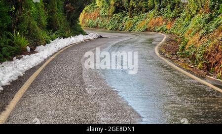 Die Manaia Road schlängelt sich bis zu den Dawson Falls (Te Rere o Noke) am Fuße des Mt. Taranaki. Nach einem leichten Schneefall im Egmont National Park, Neuseeland. Stockfoto