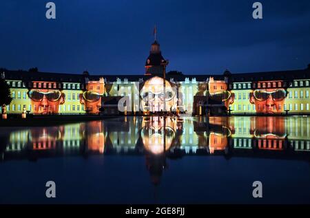 Karlsruhe, Deutschland. August 2021. Eine Probe für die Schlosslichtspiele Karlsruhe 2021 findet im Schloss Karlsruhe statt. Gezeigt wird die Projektion 'GANESIS' von Spiegelball aus dem Jahr 2021, die sich in einer Wasseroberfläche widerspiegelt. Nach einem Jahr im virtuellen Raum kann das Publikum ab dem 18. August 2021 wieder die Schlosslichtspiele auf der façade des Karlsruher Schlosses bestaunen. Bis zum 3. Oktober werden an elf Standorten in der Innenstadt jeden Abend Lichtinstallationen und Beleuchtungen gezeigt. Quelle: Uli Deck/dpa/Alamy Live News Stockfoto