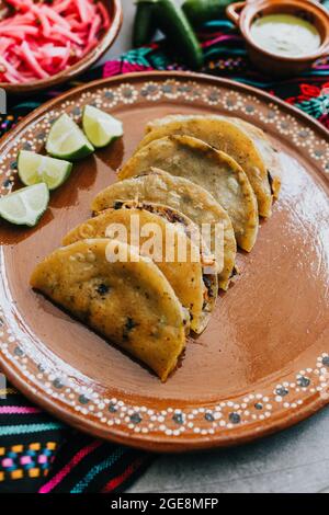 Gebratene oder gebräunte mexikanische Tacos mit Zitrone und Salsa, traditionelle mexikanische Küche in Mexiko Stockfoto