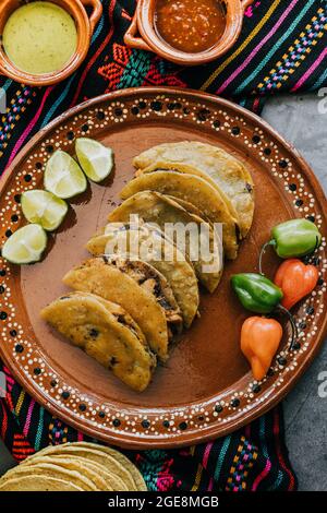 Gebratene oder gebräunte mexikanische Tacos mit Zitrone und Salsa, traditionelle mexikanische Küche in Mexiko Stockfoto