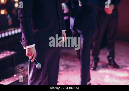 Mann in schwarzem Anzug, der das Mikrofon in der Hand hält. Stockfoto