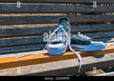 Neue Sport-Sneaker zum Laufen oder Gehen, liegen im Sommer auf einer Parkbank Stockfoto