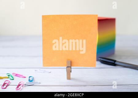 Unbeschriftete Haftnotiz Mit Laundry Clip Stapel Farbenfroher Papierschreiber Auf Dem Tisch. Leeres Blatt Wurde Neben Stift Und Auffälligen Papieren Auf Dem Schreibtisch Abgeschnitten. Stockfoto