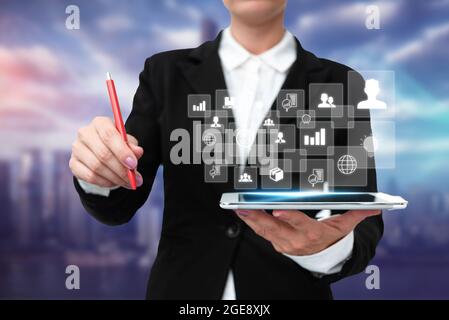Lady In Uniform Stehend Halten Tablet Und Praktisch Tippen Mit Pen. Business Woman Carrying Pad Tippen Und Anzeigen Neuer Futuristischer Technologien. Stockfoto