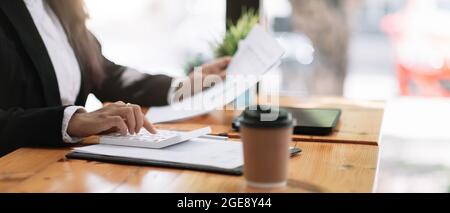 Buchhalter, der am Schreibtisch arbeitet und einen Rechner für die Berechnung des Finanzberichts im Café verwendet. Stockfoto