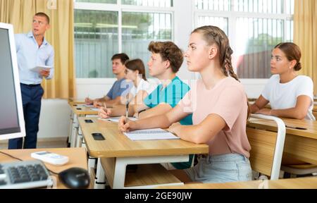 Jugendliche hören dem Dozenten zu und schreiben in Notizbüchern Stockfoto