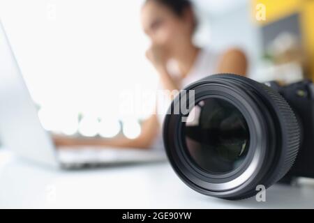 Kameraobjektiv auf dem Hintergrund einer Frau, die am Computer arbeitet Stockfoto