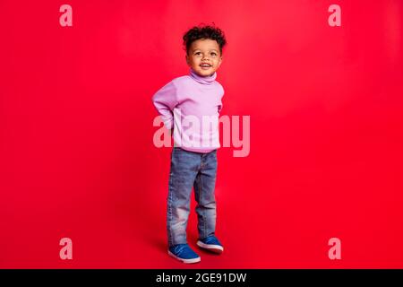 In voller Länge Körpergröße Ansicht der attraktiven fröhlich preteen Kerl gute Laune über hellen roten Hintergrund isoliert Stockfoto