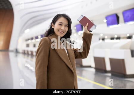 Junge chinesische Geschäftsfrau mit Flugticket am Flughafen Stockfoto