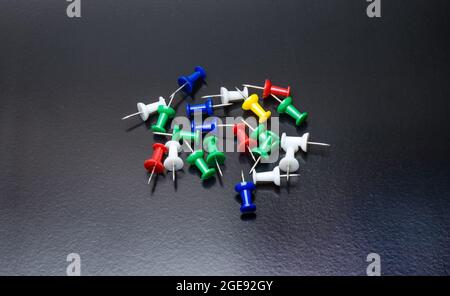 Eine Reihe von bunten Papier Push-Pins oder Daumennacks auf hellen dunklen rauen Hintergrund Stockfoto