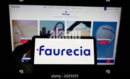 Person, die das Smartphone mit dem Logo des französischen Automobilzulieferers Faurecia SE auf dem Bildschirm vor der Website hält. Konzentrieren Sie sich auf die Telefonanzeige. Stockfoto