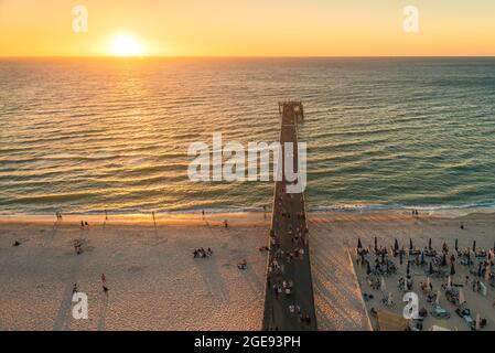 Glenelg Beach mit Menschen, die am Steg bei Sonnenuntergang von oben aus, South Australia, spazieren gehen Stockfoto