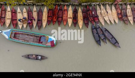 Barishal, Barishal, Bangladesch. August 2021. Bootshersteller auf dem wöchentlichen „Noukar Haat“ (Bootsmarkt) in Kuriana unter dem Swarupkathi upazila des Pirojpur-Distrikts in der Barishal Division in Bangladesch führen während dieser Monsunsaison flottes Geschäft durch. Der zwei Kilometer lange Marktplatz ist bekannt für den Handel mit verschiedenen Bootssorten während der Monsunsaison. Der Markt findet jeden Freitag von Mai bis November statt. 'Panis' oder 'Pinis'', 'Dingi' und 'Naak Golui' sind die zum Verkauf stehenden Boote, die von lokalen Handwerkern aus Muktahar, Chami, Boldia, Inderhaat, B gebaut wurden Stockfoto