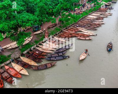 Barishal, Barishal, Bangladesch. August 2021. Bootshersteller auf dem wöchentlichen „Noukar Haat“ (Bootsmarkt) in Kuriana unter dem Swarupkathi upazila des Pirojpur-Distrikts in der Barishal Division in Bangladesch führen während dieser Monsunsaison flottes Geschäft durch. Der zwei Kilometer lange Marktplatz ist bekannt für den Handel mit verschiedenen Bootssorten während der Monsunsaison. Der Markt findet jeden Freitag von Mai bis November statt. 'Panis' oder 'Pinis'', 'Dingi' und 'Naak Golui' sind die zum Verkauf stehenden Boote, die von lokalen Handwerkern aus Muktahar, Chami, Boldia, Inderhaat, B gebaut wurden Stockfoto