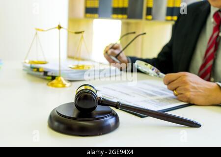 Rechtsanwalt oder Richter betrachten das Dokument mit einer Lupe, um es gründlich zu untersuchen gavel auf dem Tisch in Anwaltskanzlei vintage Ton Stockfoto