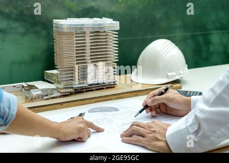 Ingenieure und Architekten diskutieren und überarbeiten Pläne für Bauvorhaben auf Grundrissen und Baumodellen. Stockfoto