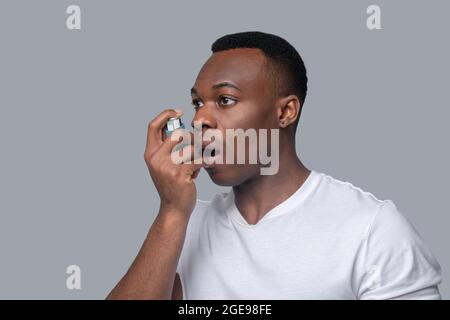 Ein dunkelhäutiger Mann in einem weißen T-Shirt fühlt sich unwohl Stockfoto