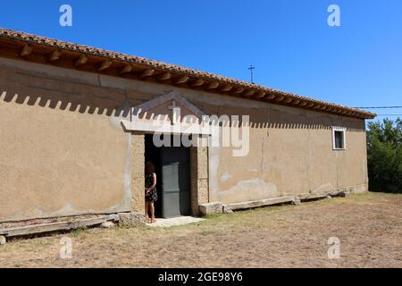 Frau, die am Eingang der Kapelle Ermita de San Roque Lantadilla Cantabria Spanien am Tag der Messe am 16. August 2021 steht Stockfoto