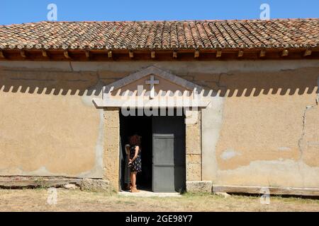 Frau, die am Eingang der Kapelle Ermita de San Roque Lantadilla Cantabria Spanien am Tag der Messe am 16. August 2021 steht Stockfoto