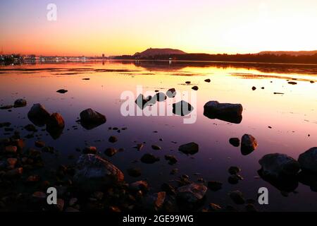 Sonnenuntergang über dem nil in Assuan, Ägypten. Sie können die Felsen und die Berge des Westufers des Nils sehen. Stockfoto