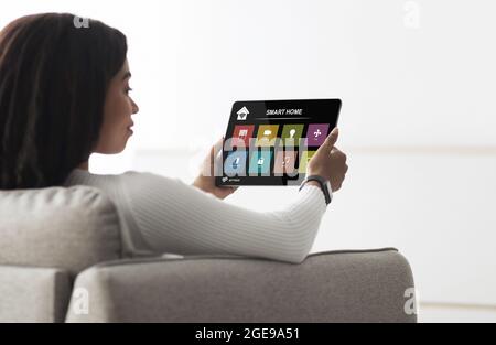 afroamerikanische Frau mit digitalem Pad und Smart House App Stockfoto